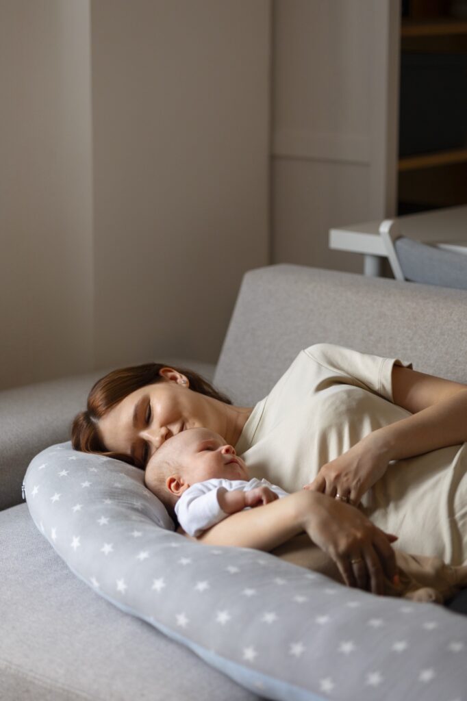 नवजात बाळ झोपले असताना विश्रांती घेत असलेली आई